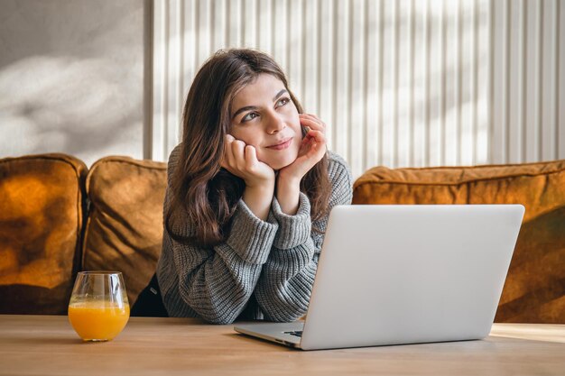 Mujer joven atractiva que trabaja en una computadora portátil temprano en la mañana