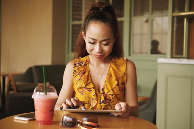 Foto gratuita mujer joven atractiva que usa la aplicación en tableta