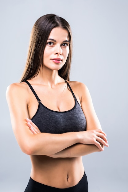 Mujer joven atractiva en ropa deportiva posando en gris.