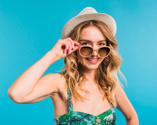 Mujer joven atractiva sonriente en sombrero y gafas de sol