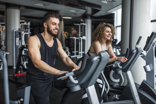 Mujer joven atractiva y su entrenador corriendo en cinta en el gimnasio