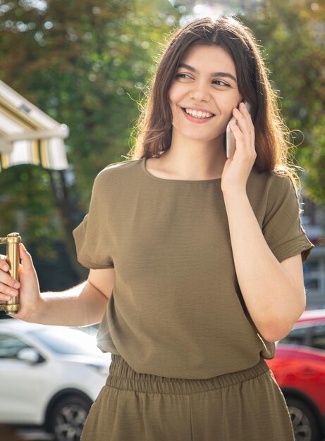 Mujer joven atractiva con un teléfono inteligente en el fondo de la calle