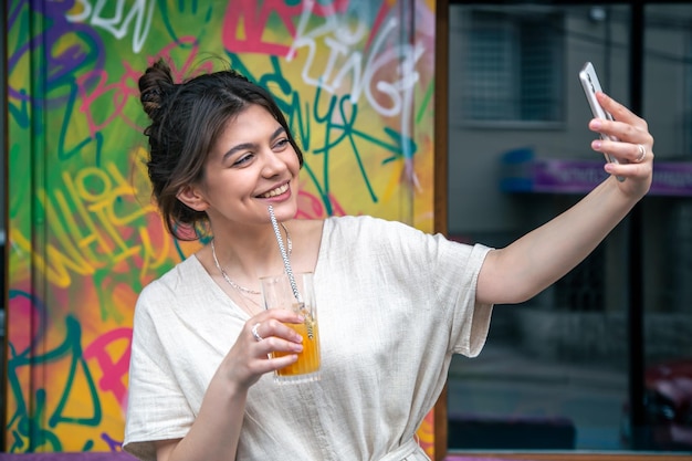 Mujer joven atractiva toma un selfie con un vaso de limonada