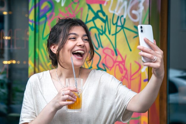 Mujer joven atractiva toma un selfie con un vaso de limonada