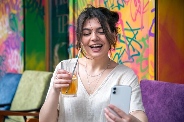 Mujer joven atractiva toma un selfie con un vaso de limonada