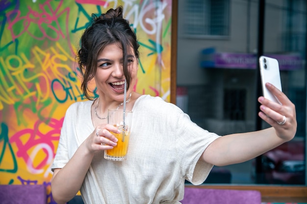 Mujer joven atractiva toma un selfie con un vaso de limonada