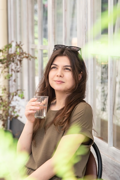 Mujer joven atractiva con un vaso de agua en un día de verano en la terraza de un café