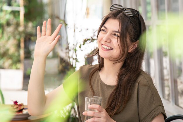 Mujer joven atractiva con un vaso de agua en un día de verano en la terraza de un café