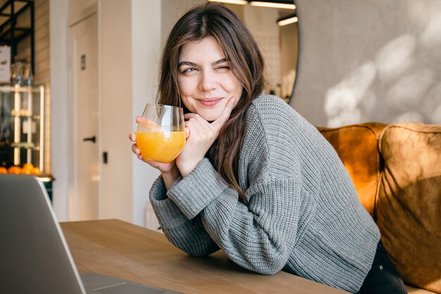 Mujer joven atractiva con un vaso de jugo de naranja recién exprimido