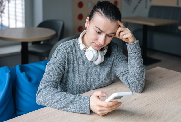 Una mujer joven con auriculares blancos y un teléfono inteligente.