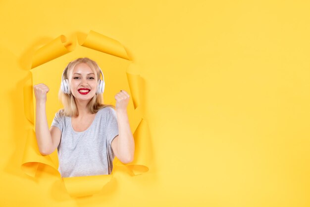 Mujer joven en auriculares sobre fondo amarillo suena audio de música de ultrasonido