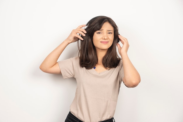 Mujer joven con auriculares sobre fondo blanco.