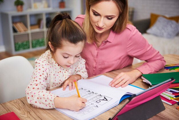 Mujer joven, ayudar, niña, con, tarea