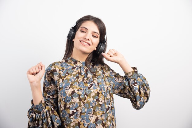 Mujer joven bailando alegremente y escuchando música en auriculares.