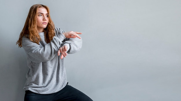 Mujer joven bailando contra la pared gris