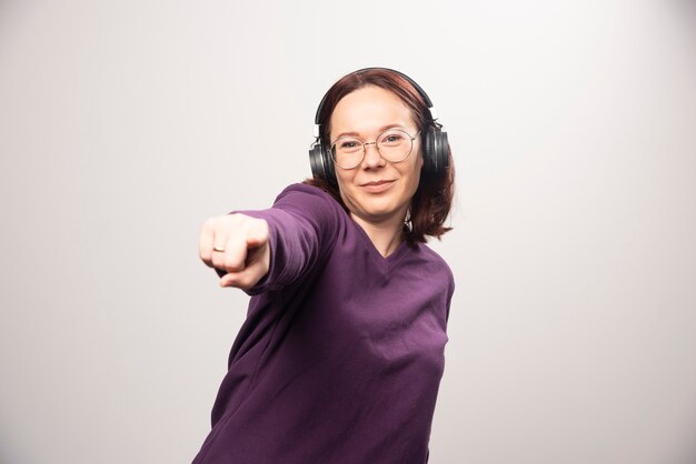 Mujer joven bailando y escuchando música en auriculares sobre un fondo blanco. Foto de alta calidad