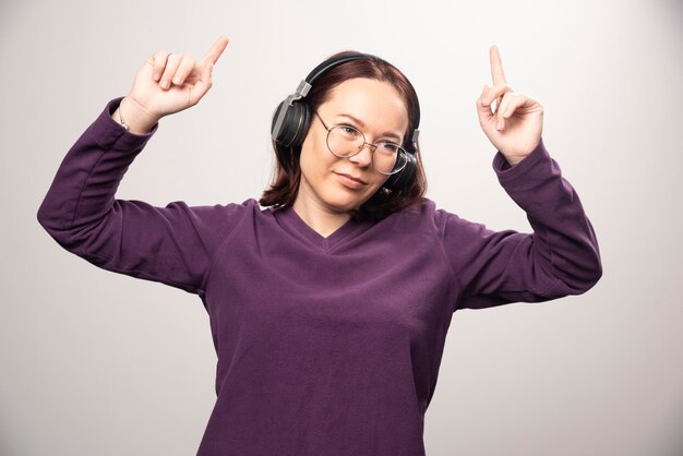 Mujer joven bailando y escuchando música en auriculares sobre un fondo blanco. Foto de alta calidad