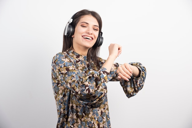 Mujer joven bailando y escuchando música en auriculares.
