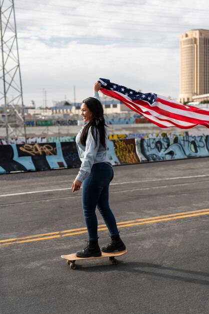 Mujer joven con bandera de estados unidos en patineta