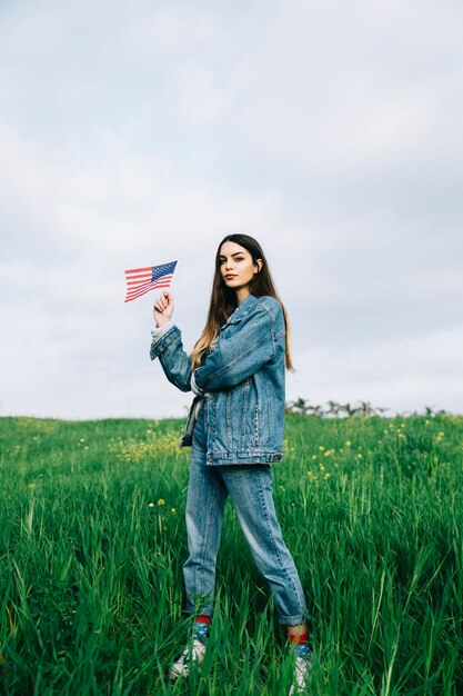 Mujer joven con bandera estadounidense en campo