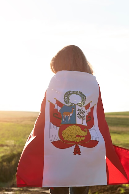 Mujer joven con bandera de perú al aire libre