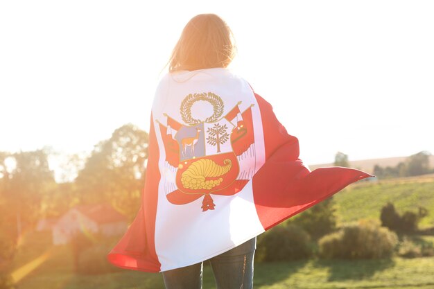 Mujer joven con bandera de perú al aire libre