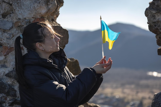 Una mujer joven con la bandera de ucrania en sus manos.