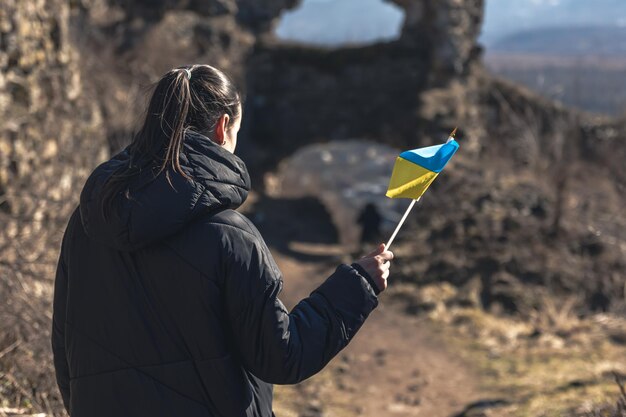Una mujer joven con la bandera de ucrania en sus manos.