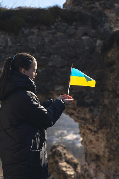 Una mujer joven con la bandera de ucrania en sus manos.