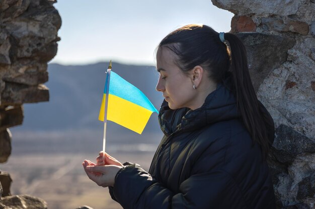 Una mujer joven con la bandera de ucrania en sus manos.
