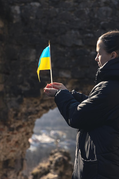 Foto gratuita una mujer joven con la bandera de ucrania en sus manos.