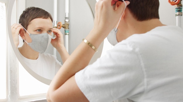 La mujer joven en el baño se puso la mascarilla