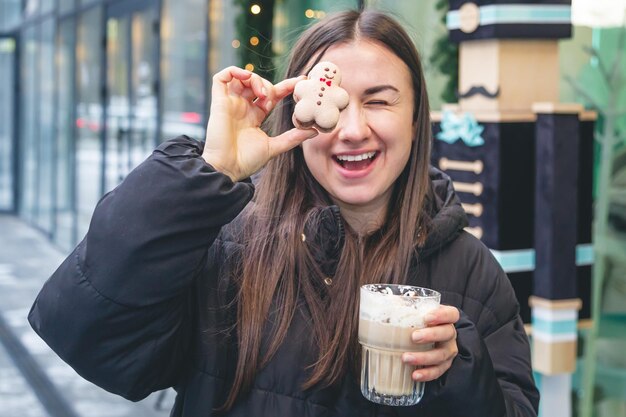 Foto gratuita una mujer joven bebe café con un chico de pan de jengibre en un café en la calle