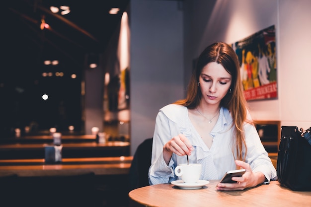 Mujer joven con bebida de mezcla de teléfono inteligente