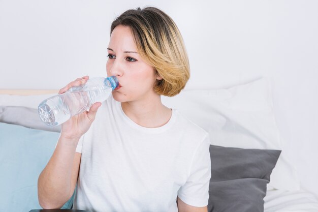 Mujer joven bebiendo agua de botella