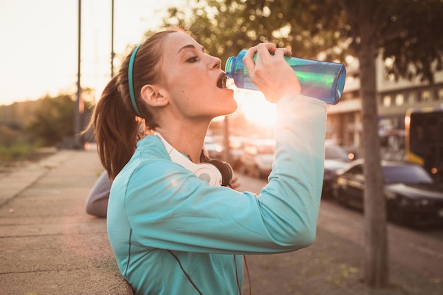 Mujer joven bebiendo agua después de hacer deporte