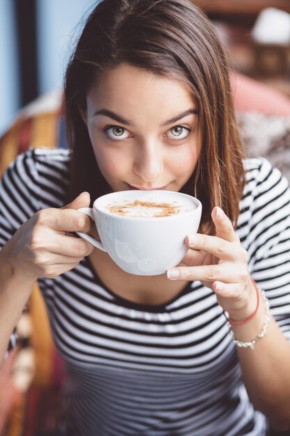 Mujer joven bebiendo café en café urbano