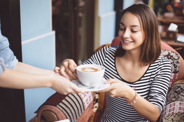 Mujer joven bebiendo café en café urbano