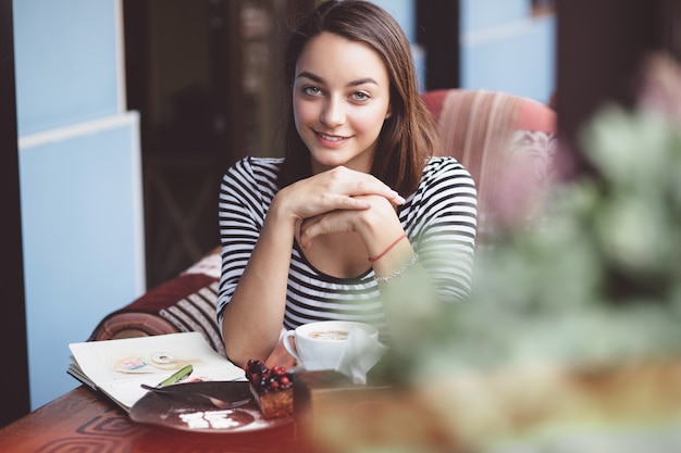 Mujer joven bebiendo café en café urbano