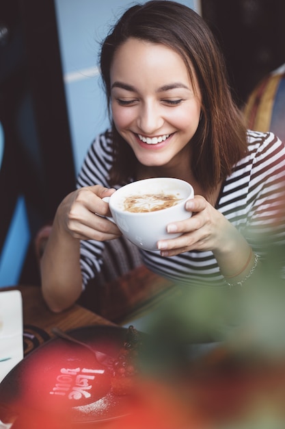 Mujer joven bebiendo café en café urbano