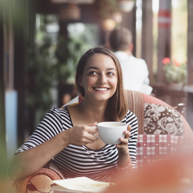 Foto gratuita mujer joven bebiendo café en café urbano