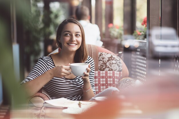 Mujer joven bebiendo café en café urbano