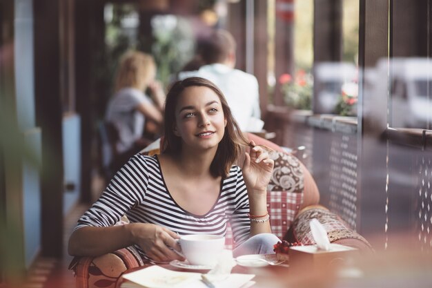 Mujer joven bebiendo café en café urbano