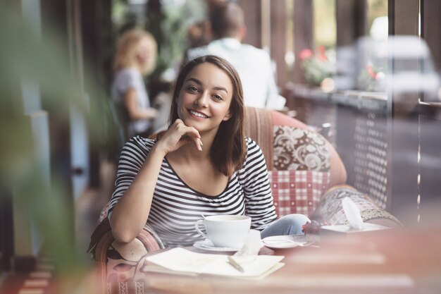 Mujer joven bebiendo café en café urbano