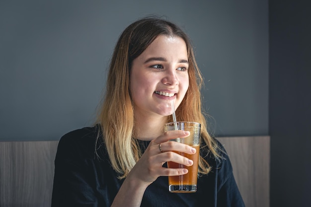 Una mujer joven bebiendo café frío de verano con hielo y jugo de naranja