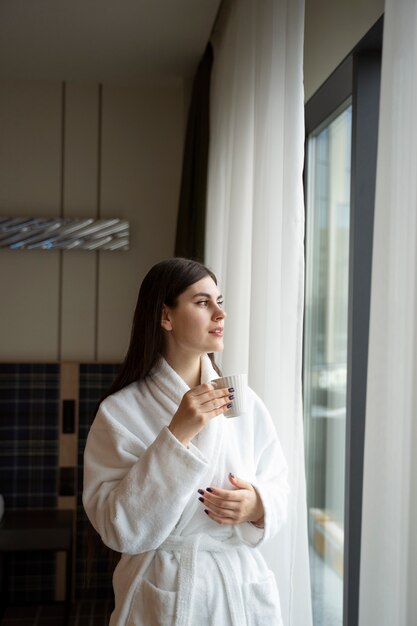 Mujer joven bebiendo café en una habitación de hotel