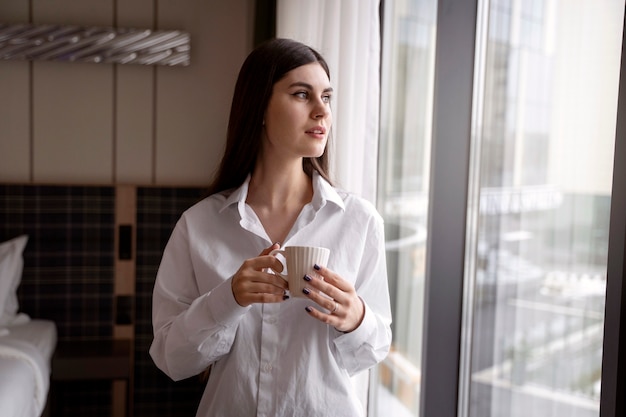 Mujer joven bebiendo café en una habitación de hotel