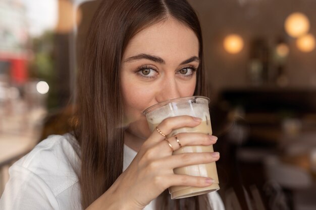 Mujer joven bebiendo café helado