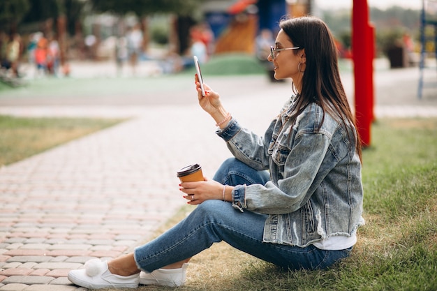 Mujer joven bebiendo café en el parque