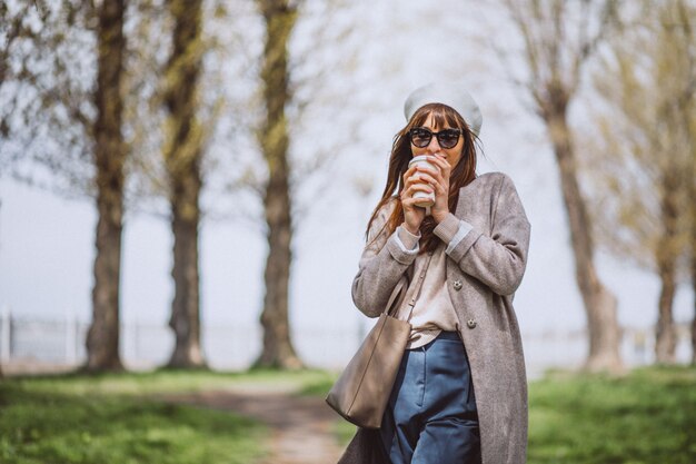 Mujer joven bebiendo café en el parque